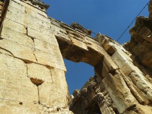 W kontekście sytuacji w sąsiedniej Syrii – Palmyra, w której mieszczą się zabytkowe runiy rzymskie przestała być całkowicie dostępna dla turystów (o ile oczywiście można uznać, że od wybuchu wojny domowej to miejsce było jakoś szczególnie przyjazne turystom) . Niestety nie mam szczególnej nadziei, że zmieni się w najbliższych latach. Nawet gdyby jednak sytuacja się poprawiła, nie ma pewności, że ocaleje cokolwiek cennego. Daily Mail opublikował ostatnio informację, że bojownicy Państwa Islamskiego zniszczyli już m.in rzeźbę lwa Al-Tat (poświęconą pre-islamskiej bogini) – to wszystko mimo wcześniejszej deklaracji, że teren wykopalisk nie zostanie ruszony. To właśnie te drastyczne wydarzenia skłoniły mnie do przeszukania archiwalnych zdjęć z Libanu, z miejscowości która znajduje się całkiem blisko granicy z Syrią. Chodzi oczywiście o Baalbek. W czasie mojego pobytu w połowie 2013 roku miasteczko świeciło pustkami – w sklepach z pamiątkami sprzedawcom nie chciało się nawet odkurzać swojego towaru – i tak tam nikt nie zaglądał. Wszystko więc było w kurzu i piachu – co oczywiście nie oznaczało, że libańscy kupcy okazali się niegościnni. Nic z tych rzeczy – częstowali słodzoną herbatą i wspominali czasy, kiedy hordy turystów z Rosji i Egiptu odwiedzały te rejony. Nie było na dobrą sprawę także gdzie zjeść – większość restauracji przy stacji autobusowej nie działała. Można za to było z łatwością kupić koszulkę lub flagę Hezbollahu. To może innym razem… Dziś sytuacja nie poprawiła się zbyt szczególnie, z tym tylko wyjątkiem, że dla bezpieczeństwa turystów, teren Heliopolis jest strzeżony przez żołnierzy libańskich. Wątpię, żeby to jakoś przekonało regularnych turystów do odwiedzin tych okolic. Nawet dość odważni podróżnicy opowiadali, że zrezygnowali z wyprawy w te rejony ze względu na ostrzeżenia, które usłyszeli w Bejrucie. Warto też przy okazji zaznaczyć, że większość hoteli oferuje wycieczkę do Baalbek prywatnym transportem – jest to jednak kosztowna wyprawa. Oczywiście można tam dostać się też zwyczajnym mini-busem. Na miejscu można wynająć prywatnego przewodnika, który oprowadza po terenie dawnego miasta rzymskiego. Jest duże prawdopodobieństwo, że miejsce będzie się miało dla samego siebie… A jest co oglądać – to kompleks, w którym Rzymianie oddawali cześć aż 3 różnym bogom. Największe wrażenie robi oczywiście Wielka Świątynia składająca się z 4 monumentalnych budowli i Mała Świątynia Bachusa. Zamknij oczy i przenieś się wstecz 2000 lat, kiedy chrześcijanie byli prześladowani, a prorok Mahomet urodzi się dopiero za jakieś 600 lat…