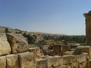 W kontekście sytuacji w sąsiedniej Syrii – Palmyra, w której mieszczą się zabytkowe runiy rzymskie przestała być całkowicie dostępna dla turystów (o ile oczywiście można uznać, że od wybuchu wojny domowej to miejsce było jakoś szczególnie przyjazne turystom) . Niestety nie mam szczególnej nadziei, że zmieni się w najbliższych latach. Nawet gdyby jednak sytuacja się poprawiła, nie ma pewności, że ocaleje cokolwiek cennego. Daily Mail opublikował ostatnio informację, że bojownicy Państwa Islamskiego zniszczyli już m.in rzeźbę lwa Al-Tat (poświęconą pre-islamskiej bogini) – to wszystko mimo wcześniejszej deklaracji, że teren wykopalisk nie zostanie ruszony. To właśnie te drastyczne wydarzenia skłoniły mnie do przeszukania archiwalnych zdjęć z Libanu, z miejscowości która znajduje się całkiem blisko granicy z Syrią. Chodzi oczywiście o Baalbek. W czasie mojego pobytu w połowie 2013 roku miasteczko świeciło pustkami – w sklepach z pamiątkami sprzedawcom nie chciało się nawet odkurzać swojego towaru – i tak tam nikt nie zaglądał. Wszystko więc było w kurzu i piachu – co oczywiście nie oznaczało, że libańscy kupcy okazali się niegościnni. Nic z tych rzeczy – częstowali słodzoną herbatą i wspominali czasy, kiedy hordy turystów z Rosji i Egiptu odwiedzały te rejony. Nie było na dobrą sprawę także gdzie zjeść – większość restauracji przy stacji autobusowej nie działała. Można za to było z łatwością kupić koszulkę lub flagę Hezbollahu. To może innym razem… Dziś sytuacja nie poprawiła się zbyt szczególnie, z tym tylko wyjątkiem, że dla bezpieczeństwa turystów, teren Heliopolis jest strzeżony przez żołnierzy libańskich. Wątpię, żeby to jakoś przekonało regularnych turystów do odwiedzin tych okolic. Nawet dość odważni podróżnicy opowiadali, że zrezygnowali z wyprawy w te rejony ze względu na ostrzeżenia, które usłyszeli w Bejrucie. Warto też przy okazji zaznaczyć, że większość hoteli oferuje wycieczkę do Baalbek prywatnym transportem – jest to jednak kosztowna wyprawa. Oczywiście można tam dostać się też zwyczajnym mini-busem. Na miejscu można wynająć prywatnego przewodnika, który oprowadza po terenie dawnego miasta rzymskiego. Jest duże prawdopodobieństwo, że miejsce będzie się miało dla samego siebie… A jest co oglądać – to kompleks, w którym Rzymianie oddawali cześć aż 3 różnym bogom. Największe wrażenie robi oczywiście Wielka Świątynia składająca się z 4 monumentalnych budowli i Mała Świątynia Bachusa. Zamknij oczy i przenieś się wstecz 2000 lat, kiedy chrześcijanie byli prześladowani, a prorok Mahomet urodzi się dopiero za jakieś 600 lat…